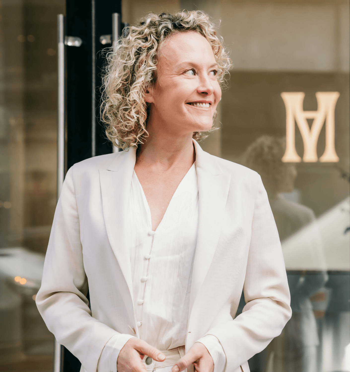 A client smiling in the Modern Age reception, the monogram on the wall behind her