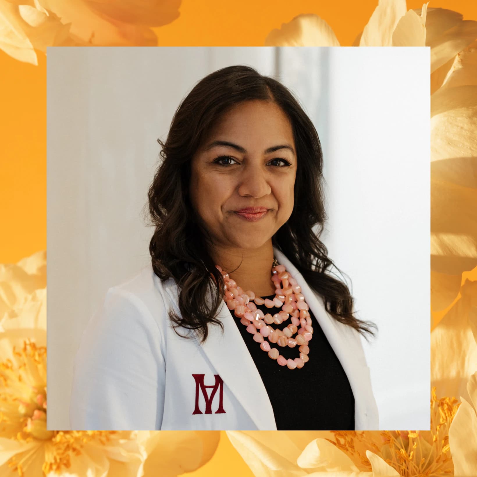 Dr. Shoma Datta-Thomas in a white coat, framed by orange flowers
