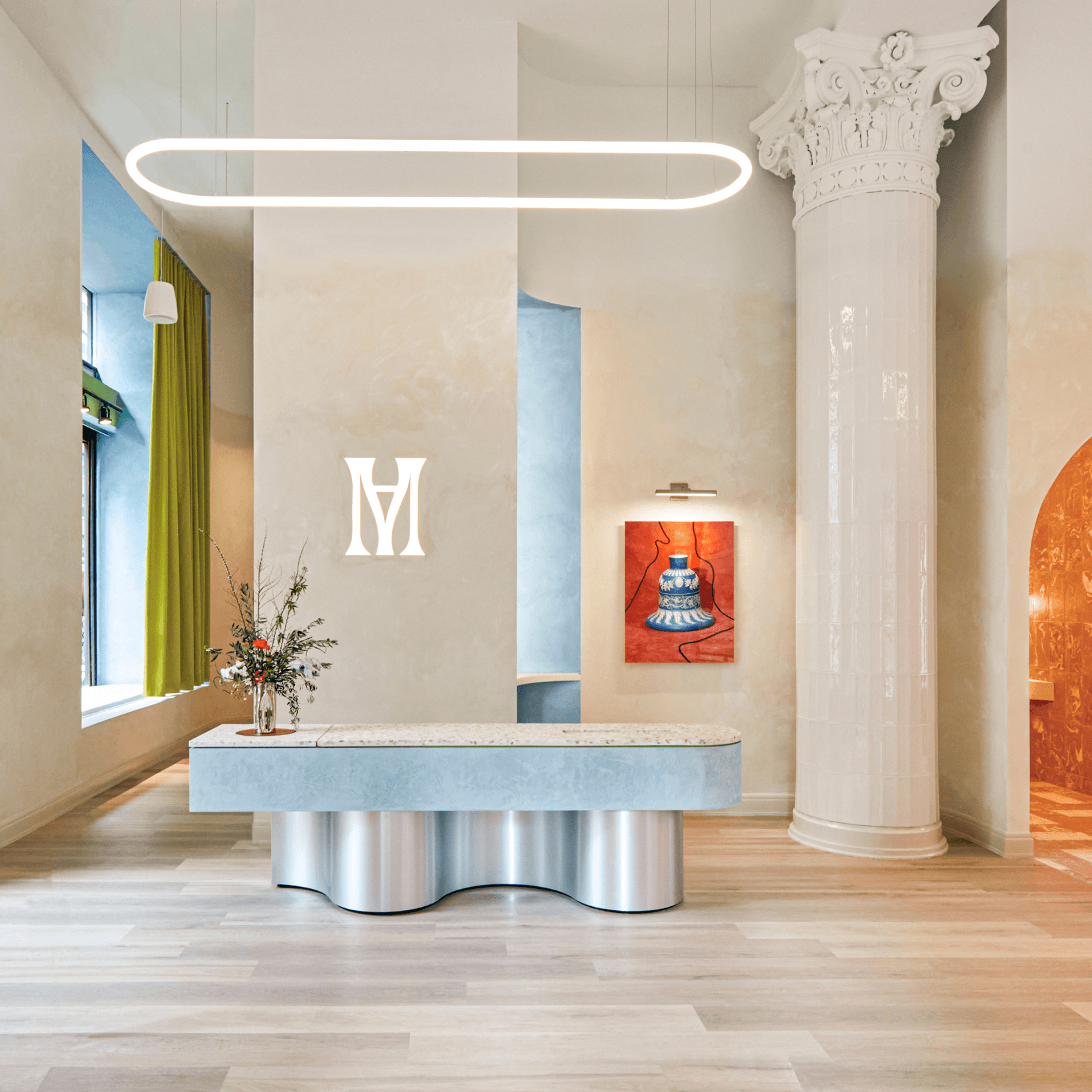 The studio lobby: white column, curved desk, the monogram on the wall